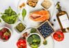 Flat lay of the best anti-inflammatory foods including salmon, berries, walnuts, spinach and turmeric on a marble surface