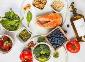 Flat lay of the best anti-inflammatory foods including salmon, berries, walnuts, spinach and turmeric on a marble surface
