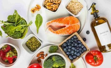 Flat lay of the best anti-inflammatory foods including salmon, berries, walnuts, spinach and turmeric on a marble surface
