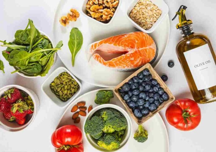 anti-inflammatory foods Flat lay of the best anti-inflammatory foods including salmon, berries, walnuts, spinach and turmeric on a marble surface