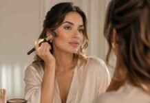 how to contour for beginners - British woman applying contour makeup with fluffy brush in front of vanity mirror using matte bronzer and highlighter – beginner contouring makeup guide UK